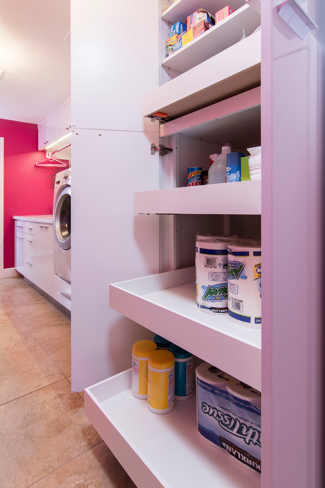 This is an example of a large contemporary galley utility room in Los Angeles with an undermount sink, flat-panel cabinets, white cabinets, quartz benchtops, pink walls, porcelain floors, a side-by-side washer and dryer and beige floor.