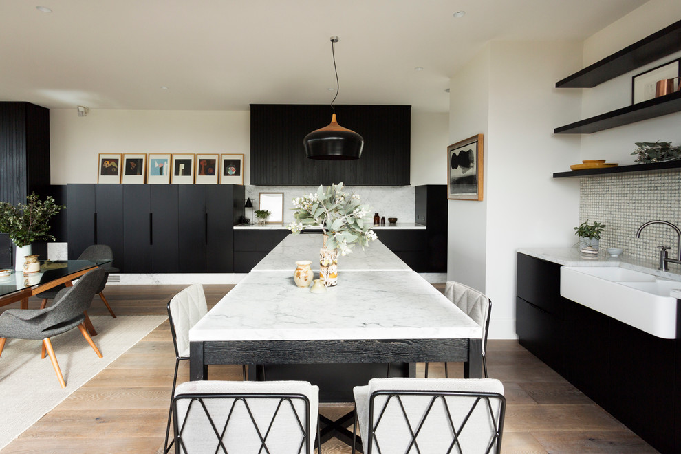 This is an example of a large scandinavian l-shaped eat-in kitchen in Melbourne with a farmhouse sink, black cabinets, marble benchtops, multi-coloured splashback, mosaic tile splashback, stainless steel appliances, medium hardwood floors, with island and flat-panel cabinets.