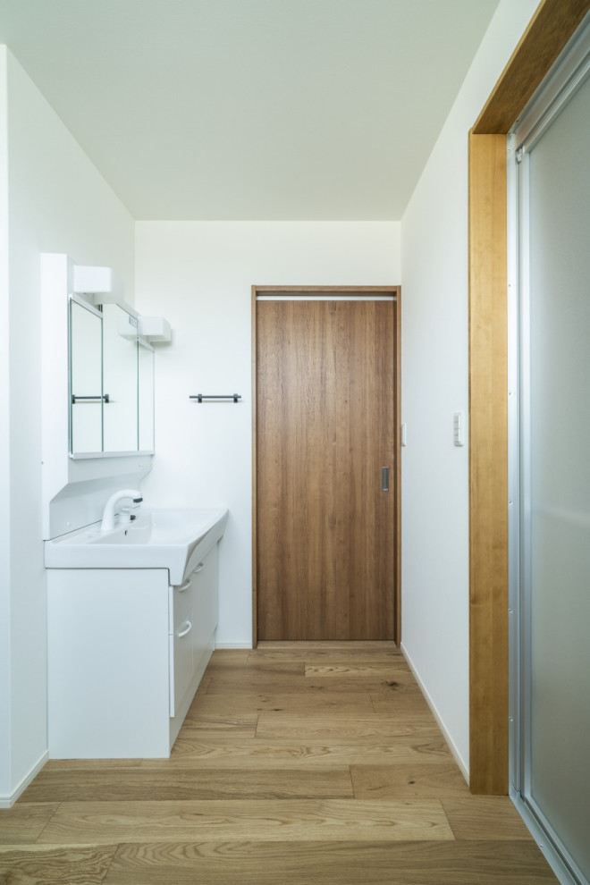 Mid-sized minimalist light wood floor, beige floor, wallpaper ceiling and wallpaper powder room photo in Other with beaded inset cabinets, white cabinets, a one-piece toilet, white walls and a freestanding vanity