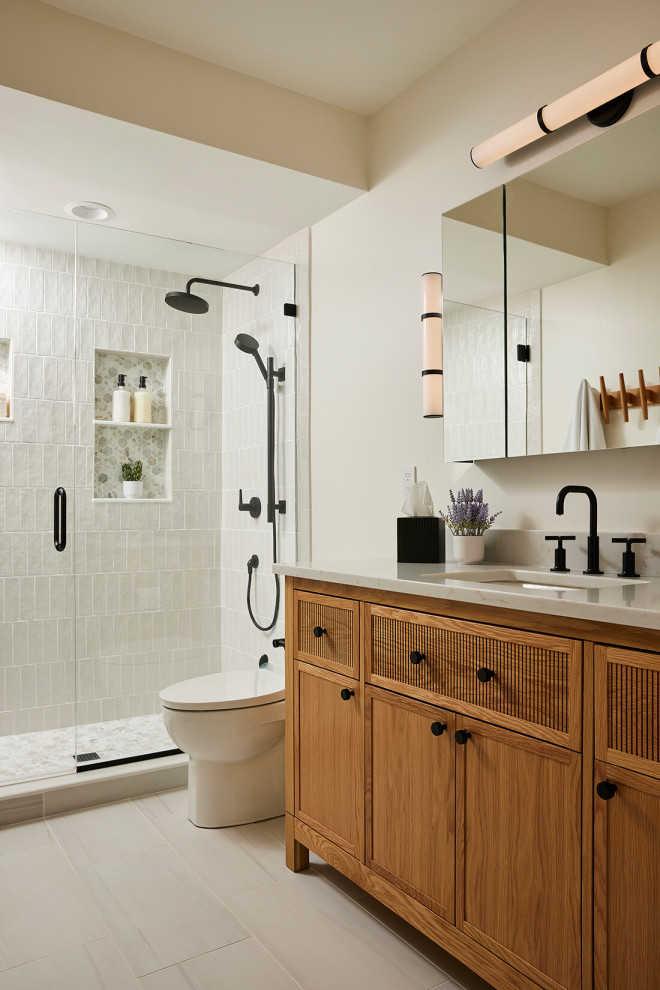 Inspiration for a transitional white tile gray floor and single-sink alcove shower remodel in Minneapolis with shaker cabinets, medium tone wood cabinets, white walls, an undermount sink, a hinged shower door, gray countertops and a freestanding vanity