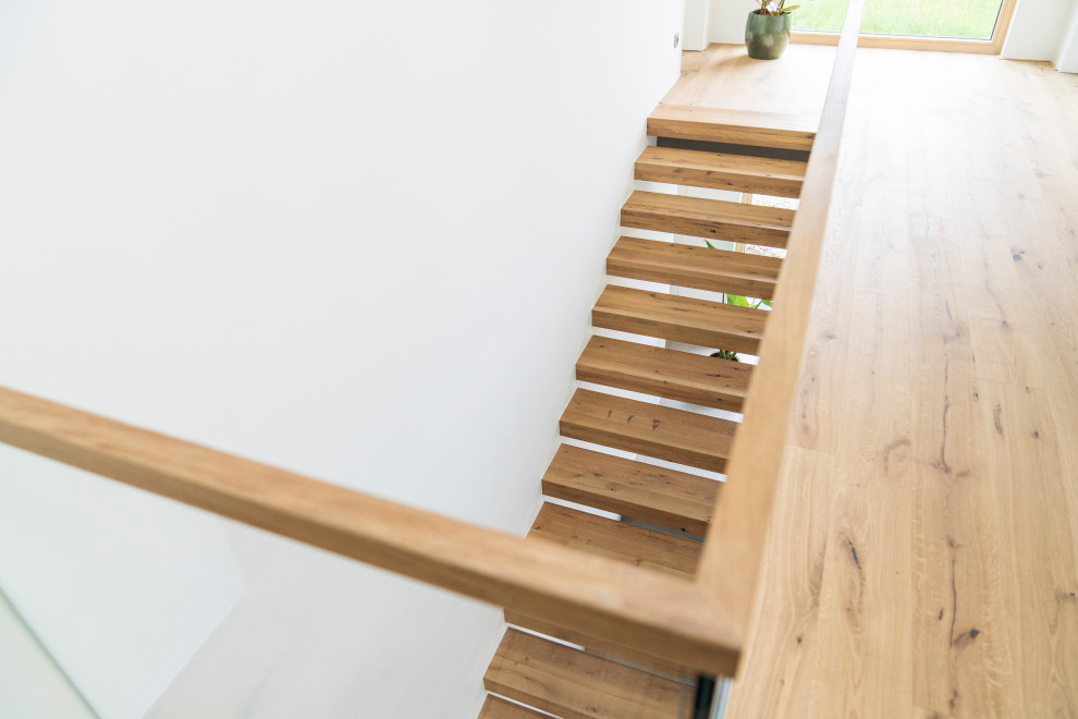Inspiration for a contemporary wood staircase in Munich with glass railing.