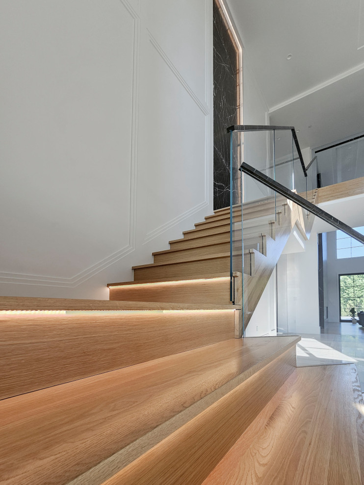 Diseño de escalera suspendida actual extra grande con escalones de madera, contrahuellas de madera, barandilla de varios materiales y boiserie