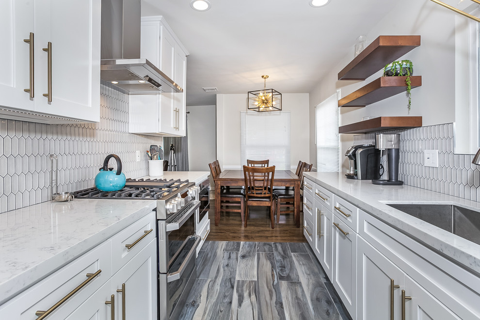Inspiration for a large modern galley eat-in kitchen in Los Angeles with an undermount sink, beaded inset cabinets, white cabinets, marble benchtops, white splashback, porcelain splashback, stainless steel appliances, vinyl floors, no island, multi-coloured floor and white benchtop.