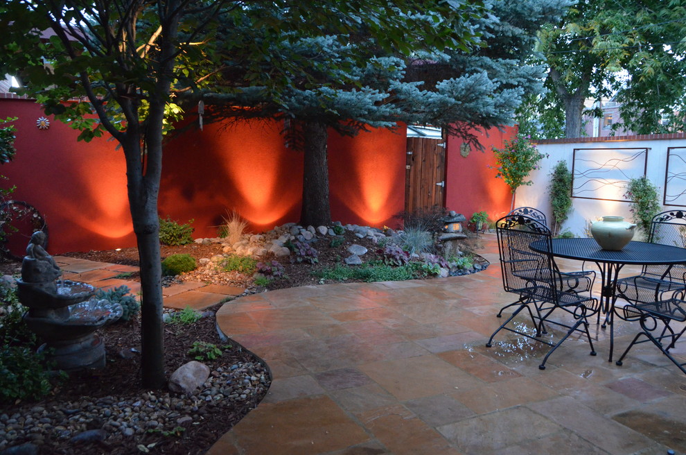 This is an example of a mid-sized asian backyard patio in Denver with a water feature and natural stone pavers.