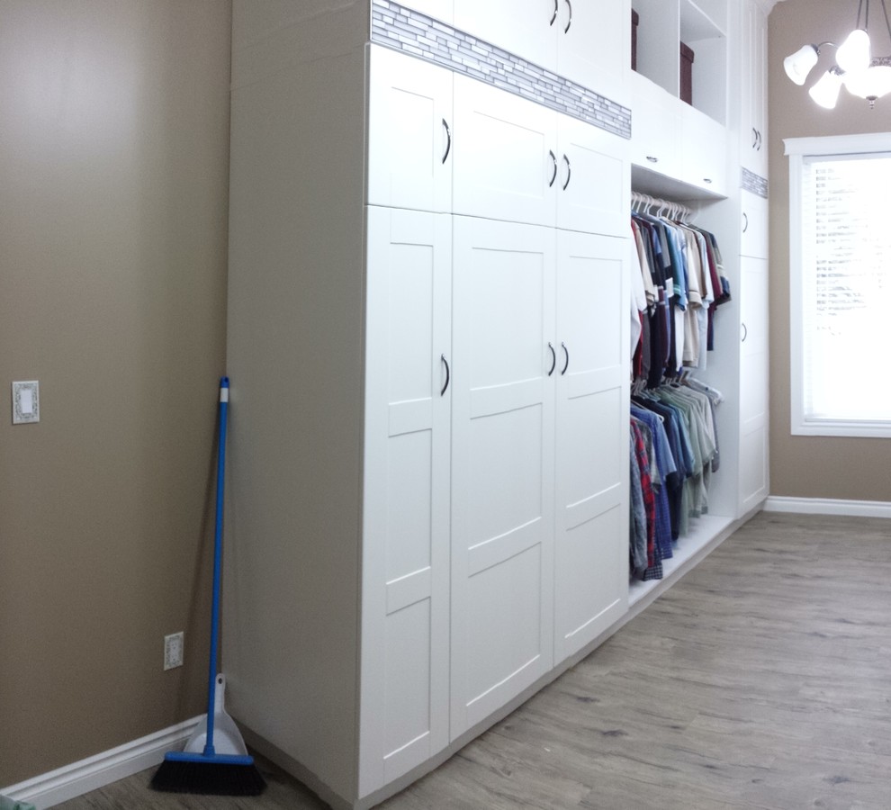 Photo of a large modern gender-neutral dressing room in Calgary with shaker cabinets, white cabinets, vinyl floors and brown floor.