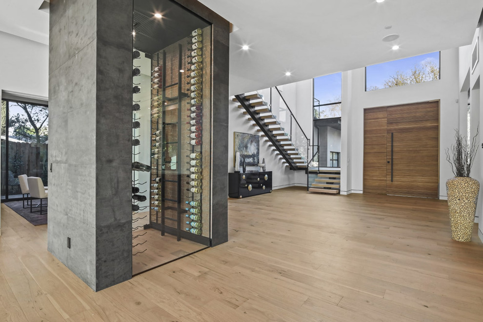 Photo of a large contemporary foyer in Los Angeles with white walls, light hardwood floors, a single front door, a medium wood front door, beige floor and vaulted.