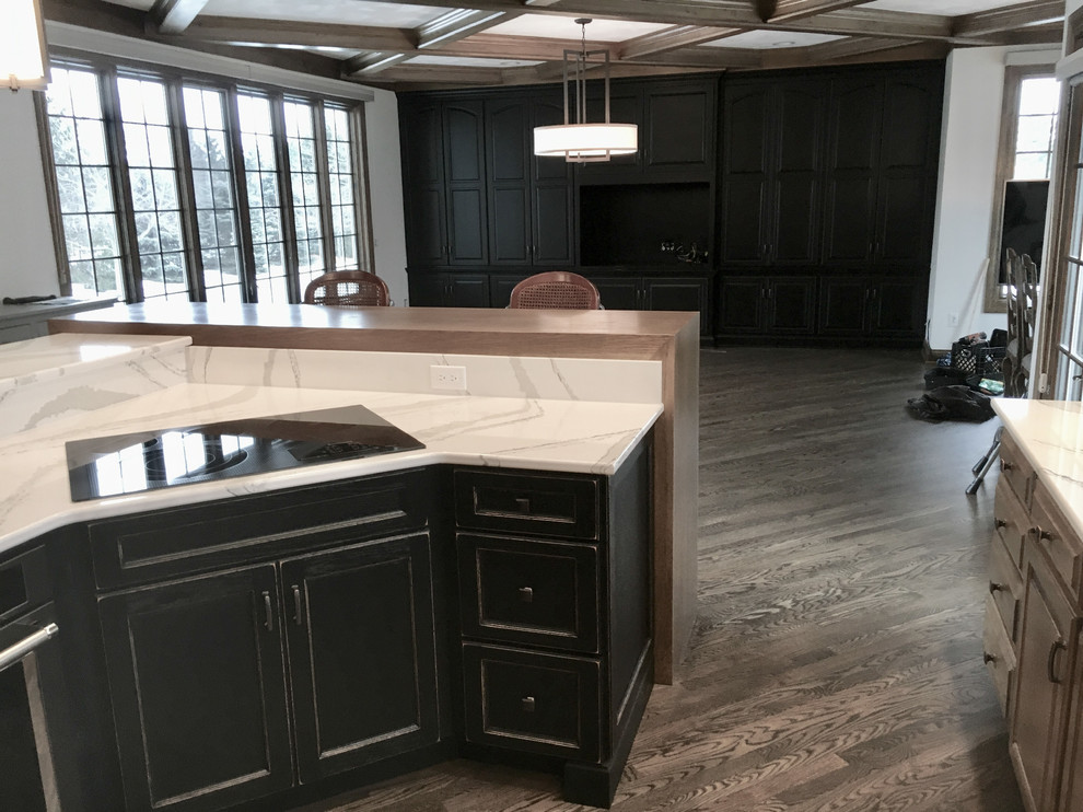 Example of a large transitional u-shaped medium tone wood floor open concept kitchen design with an undermount sink, recessed-panel cabinets, distressed cabinets, quartz countertops, multicolored backsplash, mosaic tile backsplash, stainless steel appliances and an island