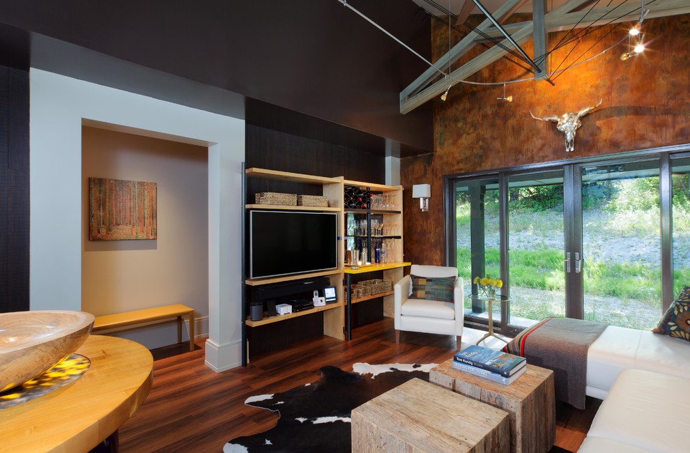 This is an example of a contemporary living room in Seattle with brown walls, dark hardwood floors, a freestanding tv and brown floor.