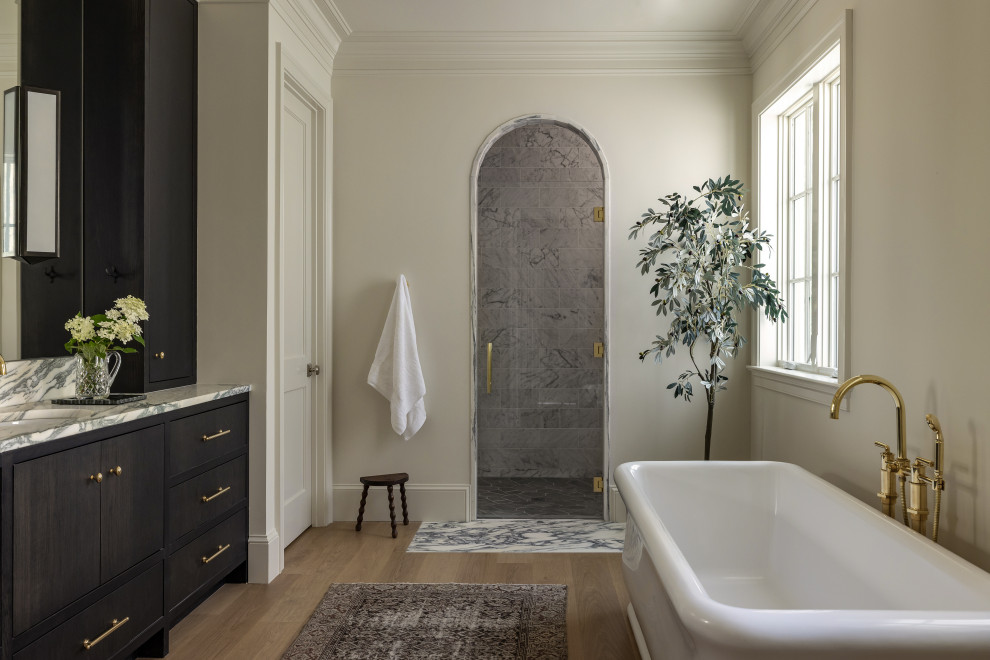 Transitional master gray tile medium tone wood floor and brown floor bathroom photo in DC Metro with flat-panel cabinets, a built-in vanity, dark wood cabinets, beige walls, an undermount sink, a hinged shower door and gray countertops