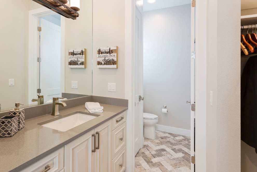 Maritim inredning av ett mellanstort brun brunt en-suite badrum, med luckor med profilerade fronter, beige skåp, en toalettstol med hel cisternkåpa, ett undermonterad handfat, marmorbänkskiva, vita väggar, marmorgolv och flerfärgat golv
