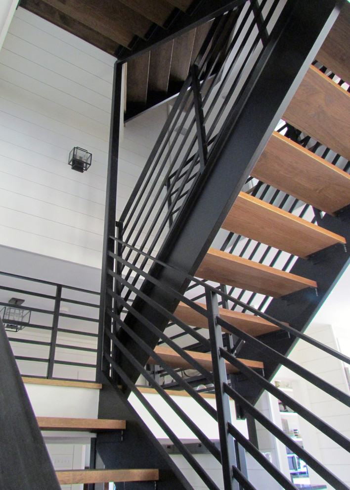 This is an example of a large modern wood u-shaped staircase in Portland Maine with open risers.