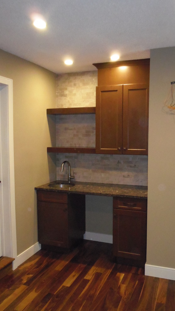 This is an example of a small transitional single-wall wet bar in Calgary with an undermount sink, dark wood cabinets, granite benchtops and beige splashback.