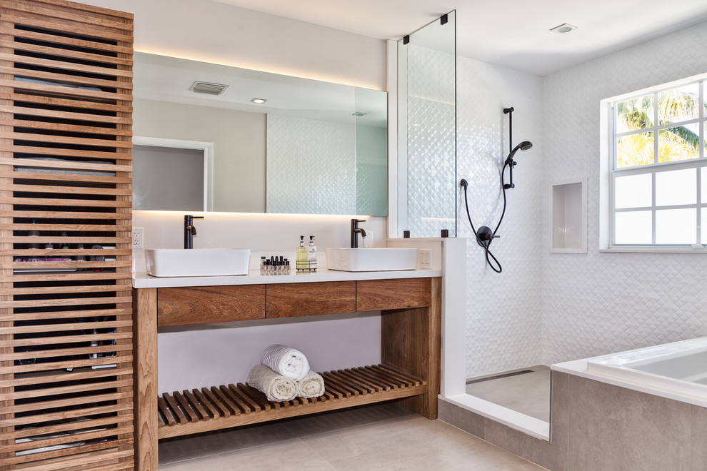 Mid-sized beach style master bathroom in Miami with medium wood cabinets, a freestanding tub, an open shower, a two-piece toilet, white tile, ceramic tile, white walls, a vessel sink, engineered quartz benchtops, beige floor, an open shower and flat-panel cabinets.