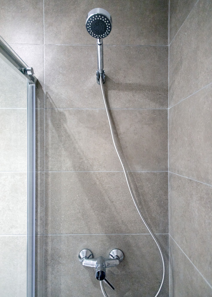 Ejemplo de cuarto de baño principal actual de tamaño medio con puertas de armario de madera oscura, ducha esquinera, sanitario de una pieza, baldosas y/o azulejos beige, suelo gris, ducha con puerta corredera y encimeras blancas