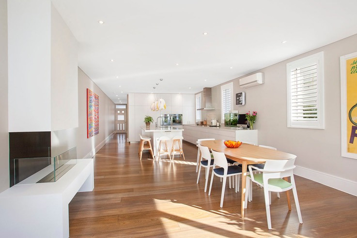 Contemporary l-shaped eat-in kitchen in Sydney with a double-bowl sink, grey cabinets, quartz benchtops, grey splashback, glass sheet splashback, stainless steel appliances, medium hardwood floors and with island.
