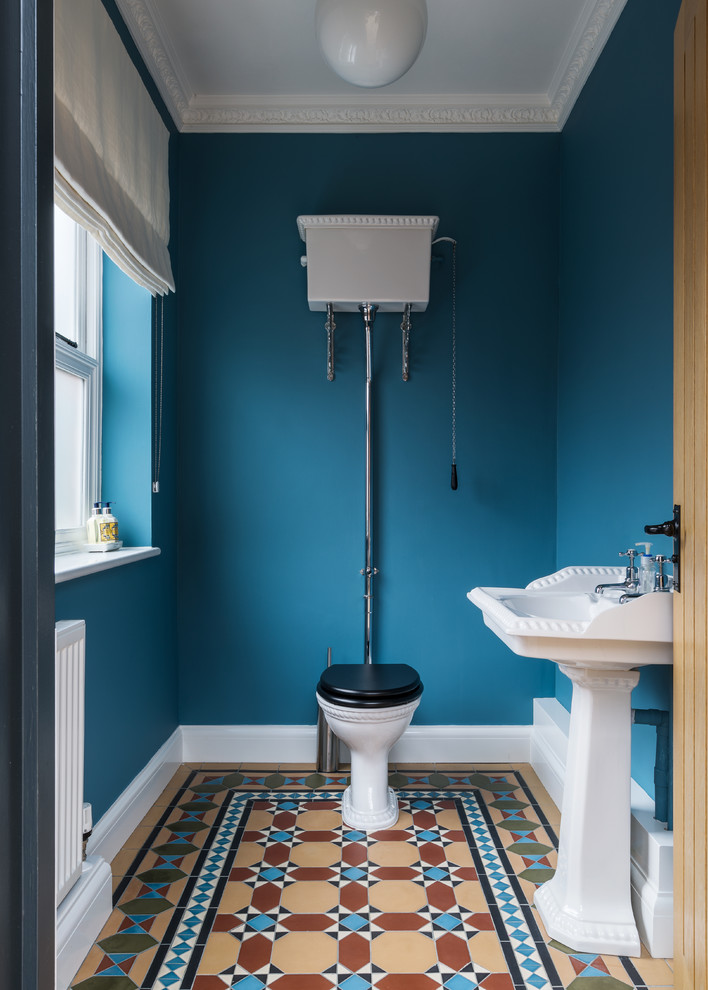 Design ideas for a mid-sized country powder room in Surrey with a two-piece toilet, blue walls and a console sink.