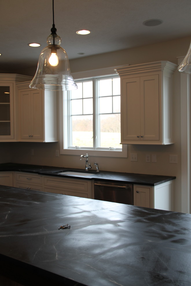 Large elegant l-shaped light wood floor eat-in kitchen photo with an undermount sink, recessed-panel cabinets, white cabinets, soapstone countertops, stainless steel appliances and an island