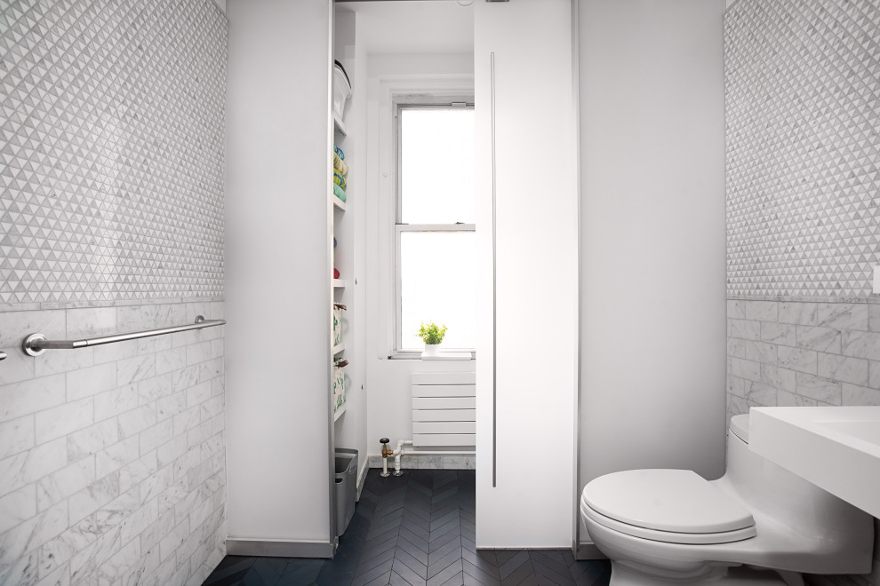 Small modern powder room in New York with a one-piece toilet, gray tile, mosaic tile, white walls, porcelain floors, a wall-mount sink, black floor, white benchtops, a freestanding vanity and decorative wall panelling.