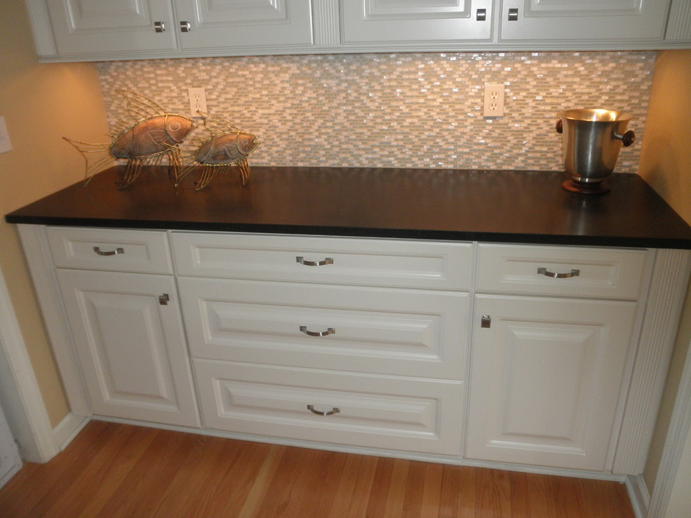 Example of a mid-sized minimalist l-shaped light wood floor eat-in kitchen design with an undermount sink, raised-panel cabinets, white cabinets, granite countertops, yellow backsplash, stone tile backsplash, stainless steel appliances, beige walls and an island