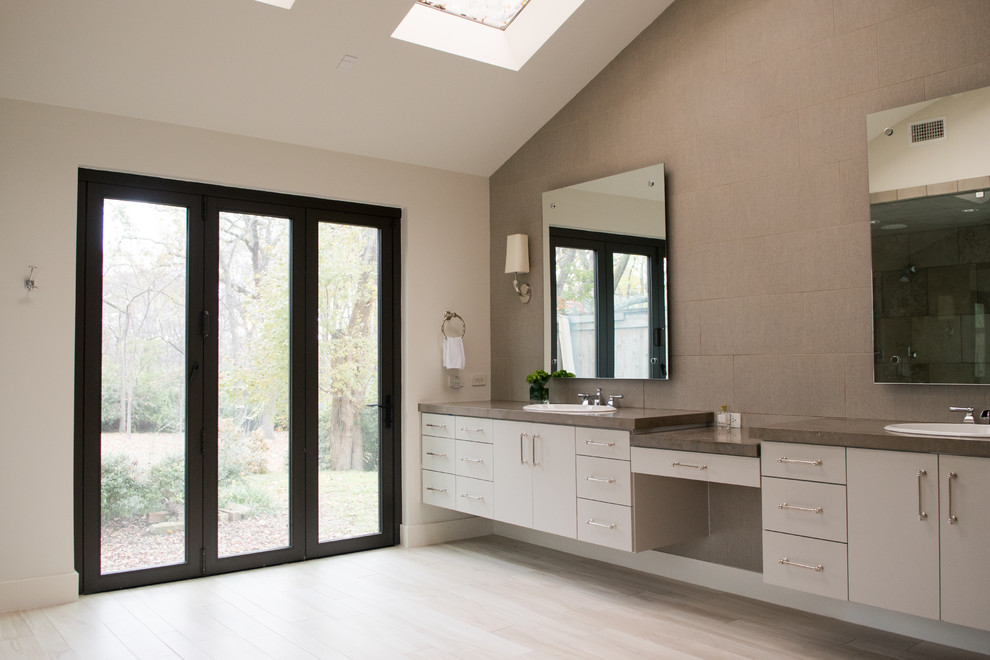 Mid-sized transitional master gray tile and cement tile light wood floor and beige floor drop-in bathtub photo in Dallas with flat-panel cabinets, gray cabinets, gray walls, a drop-in sink, concrete countertops and a hinged shower door