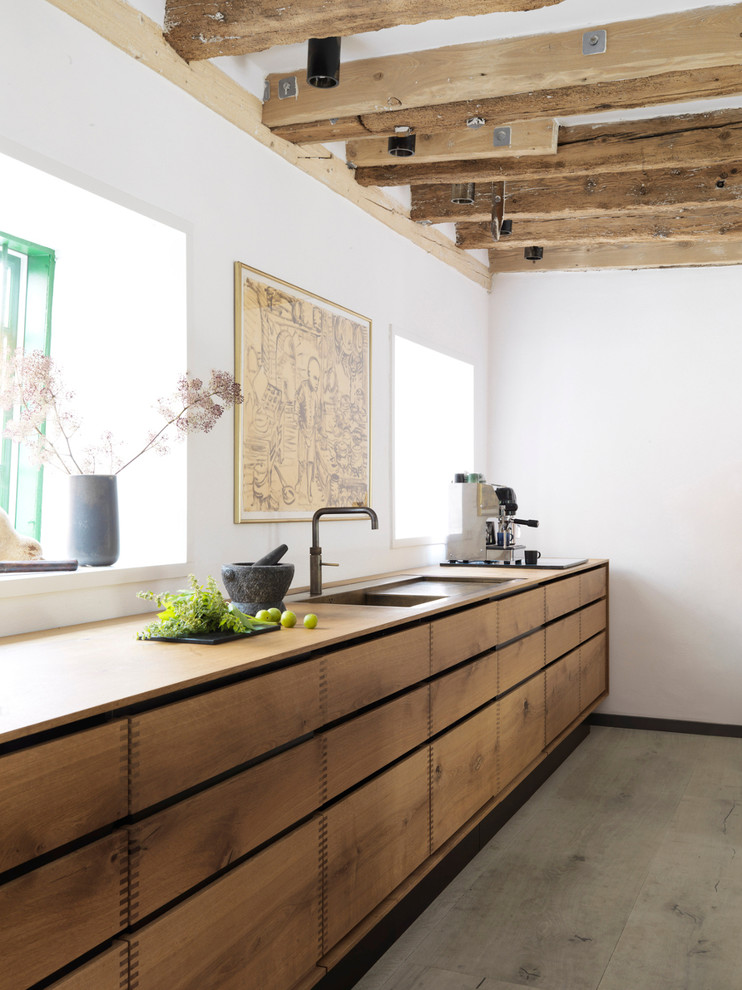 Inspiration for a large country galley open plan kitchen in Copenhagen with flat-panel cabinets, medium wood cabinets, a drop-in sink, wood benchtops, with island and painted wood floors.