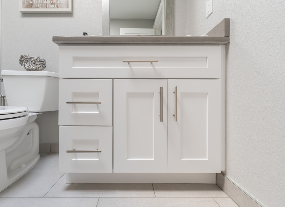 This is an example of a mid-sized contemporary kids bathroom in Seattle with recessed-panel cabinets, white cabinets, an open shower, a two-piece toilet, white tile, stone tile, grey walls, an undermount sink, engineered quartz benchtops, beige floor and a sliding shower screen.