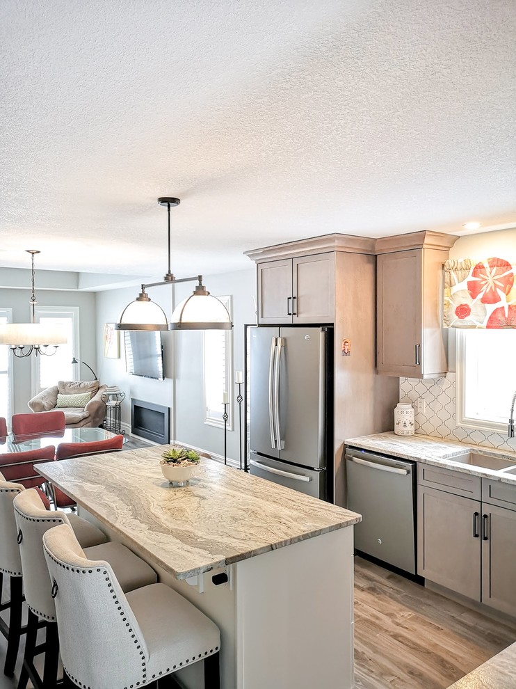 Mid-sized transitional l-shaped medium tone wood floor and brown floor open concept kitchen photo in Toronto with an undermount sink, shaker cabinets, light wood cabinets, granite countertops, white backsplash, porcelain backsplash, stainless steel appliances, an island and beige countertops