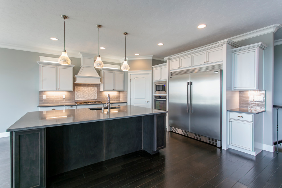 Mid-sized transitional l-shaped dark wood floor open concept kitchen photo in Seattle with an undermount sink, shaker cabinets, white cabinets, quartz countertops, gray backsplash, glass tile backsplash, stainless steel appliances and an island
