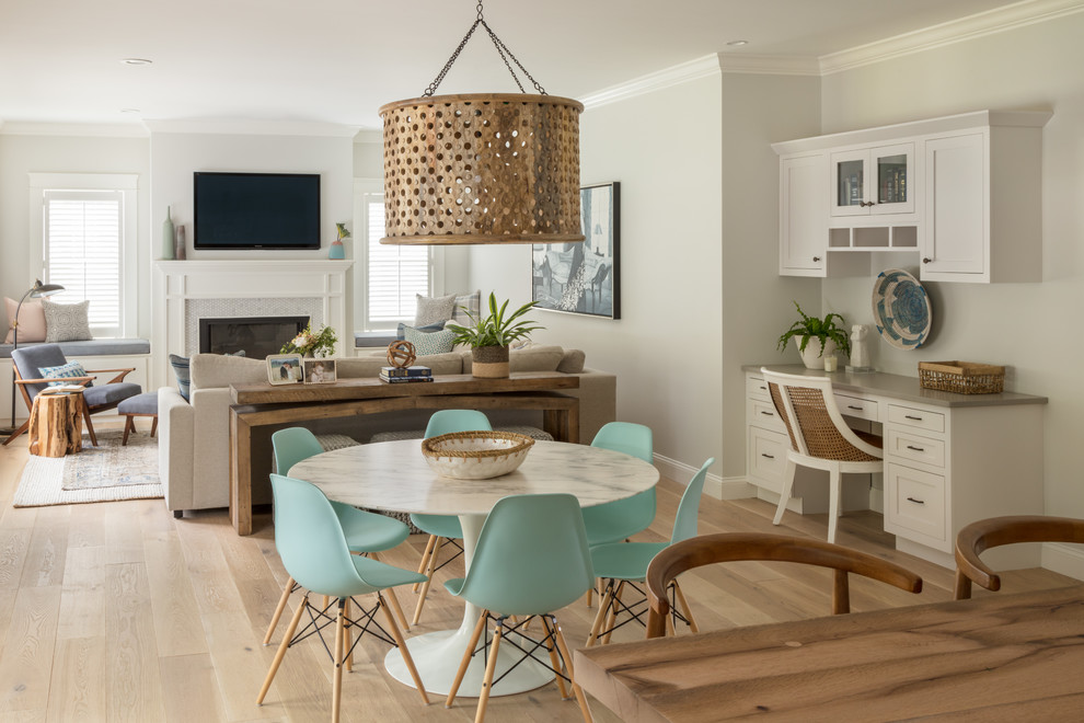 This is an example of a beach style dining room in Boston with light hardwood floors and a standard fireplace.