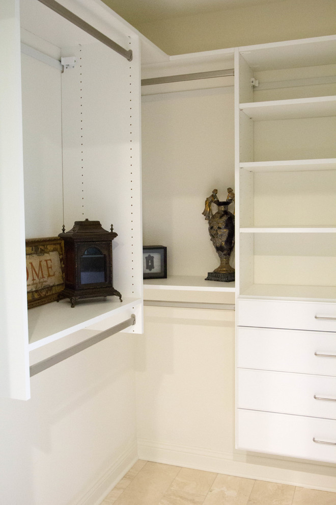 Mid-sized arts and crafts gender-neutral walk-in wardrobe in Milwaukee with flat-panel cabinets, white cabinets and travertine floors.