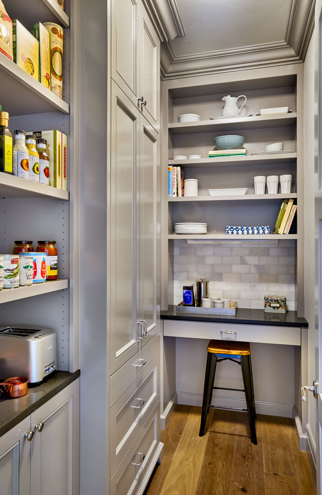 This is an example of a mid-sized traditional galley kitchen pantry in Portland with grey cabinets, recessed-panel cabinets, quartz benchtops, grey splashback, stone tile splashback, light hardwood floors and no island.