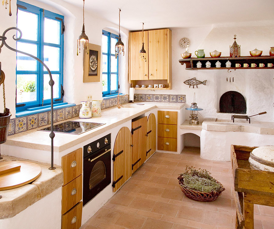 Photo of a small mediterranean u-shaped eat-in kitchen in Other with an integrated sink, open cabinets, medium wood cabinets, limestone benchtops, multi-coloured splashback, ceramic splashback, white appliances, brick floors and no island.