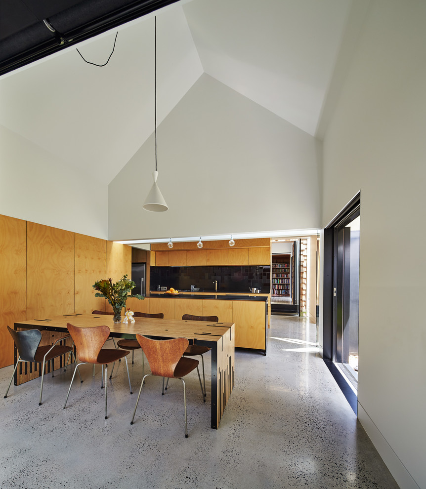 Design ideas for a mid-sized contemporary kitchen in Melbourne with flat-panel cabinets, light wood cabinets, black splashback, concrete floors and with island.