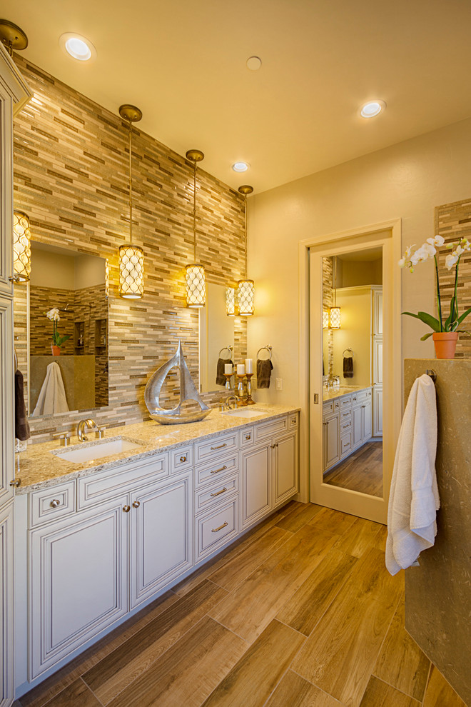 Photo of a mid-sized transitional master bathroom in Phoenix with an undermount sink, raised-panel cabinets, white cabinets, engineered quartz benchtops, a freestanding tub, a corner shower, a one-piece toilet, multi-coloured tile, mosaic tile, beige walls and porcelain floors.