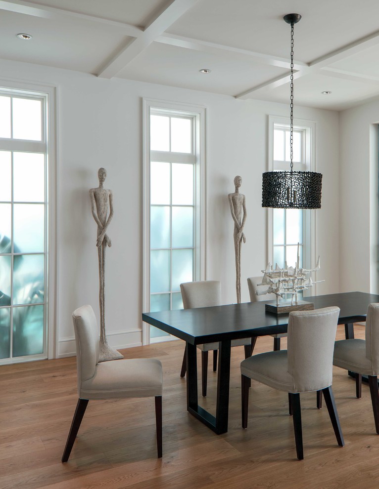 Inspiration for a beach style dining room in Miami with white walls and medium hardwood floors.