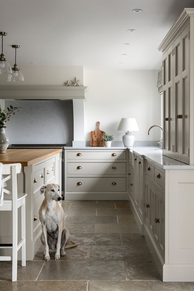 Photo of a country u-shaped kitchen/diner in Other with recessed-panel cabinets, beige cabinets, quartz worktops, stainless steel appliances, slate flooring, an island, beige worktops and a chimney breast.