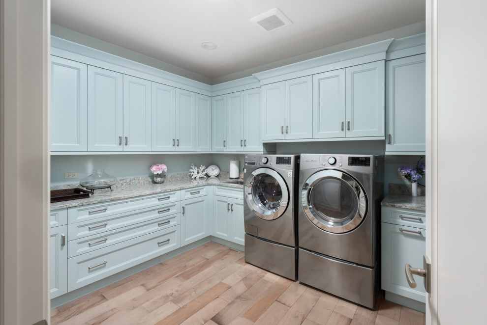 Photo of a transitional l-shaped dedicated laundry room in Chicago with an undermount sink, recessed-panel cabinets, blue cabinets, granite benchtops, granite splashback, blue walls, medium hardwood floors, a side-by-side washer and dryer, brown floor and multi-coloured benchtop.