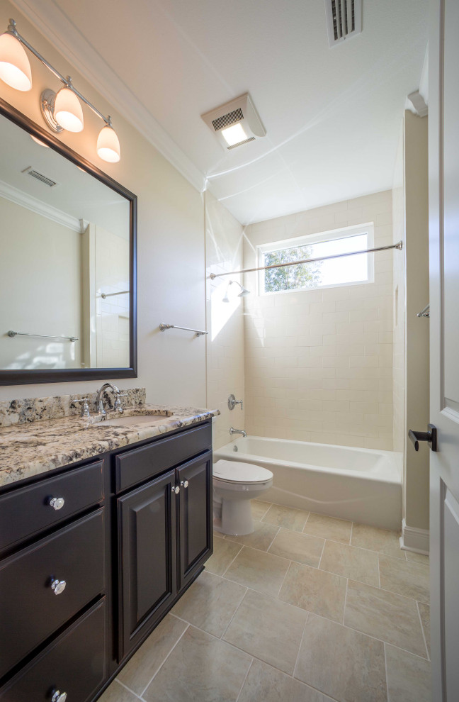 Design ideas for a mid-sized traditional kids bathroom with raised-panel cabinets, dark wood cabinets, an alcove tub, a shower/bathtub combo, a one-piece toilet, beige tile, porcelain tile, beige walls, ceramic floors, an integrated sink, granite benchtops, beige floor, a shower curtain, multi-coloured benchtops, a niche, a single vanity and a built-in vanity.