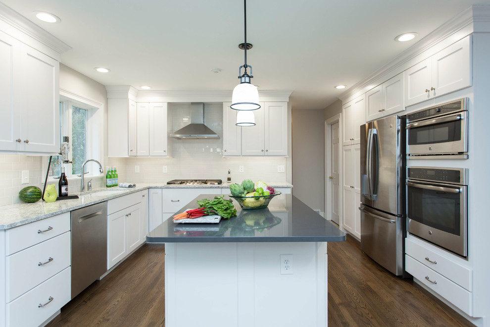 Enclosed kitchen - mid-sized transitional u-shaped dark wood floor enclosed kitchen idea in Boston with an undermount sink, recessed-panel cabinets, white cabinets, quartz countertops, gray backsplash, subway tile backsplash, stainless steel appliances and an island