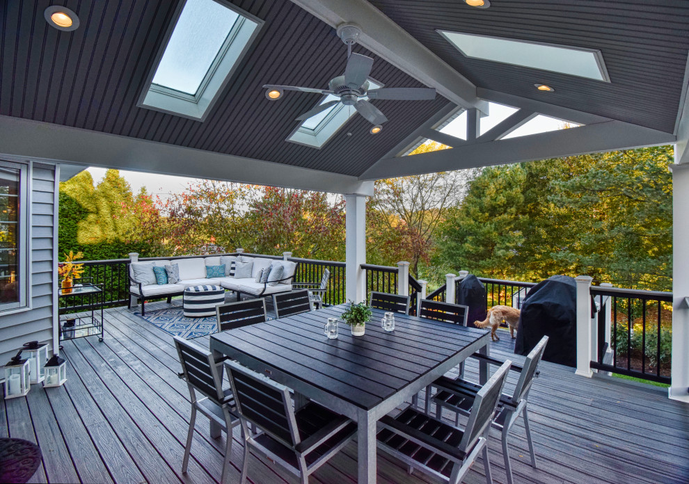 Photo of a mid-sized transitional backyard deck in Other with a roof extension.