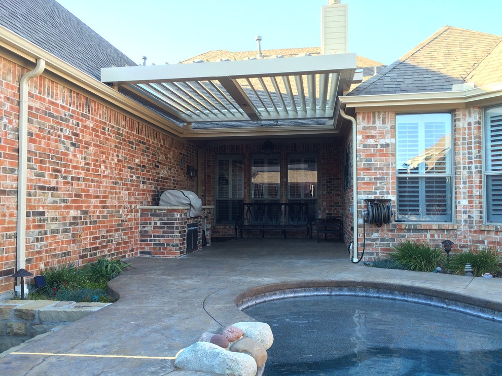 Photo of a mid-sized traditional side yard patio in Dallas with an outdoor kitchen, concrete slab and a pergola.
