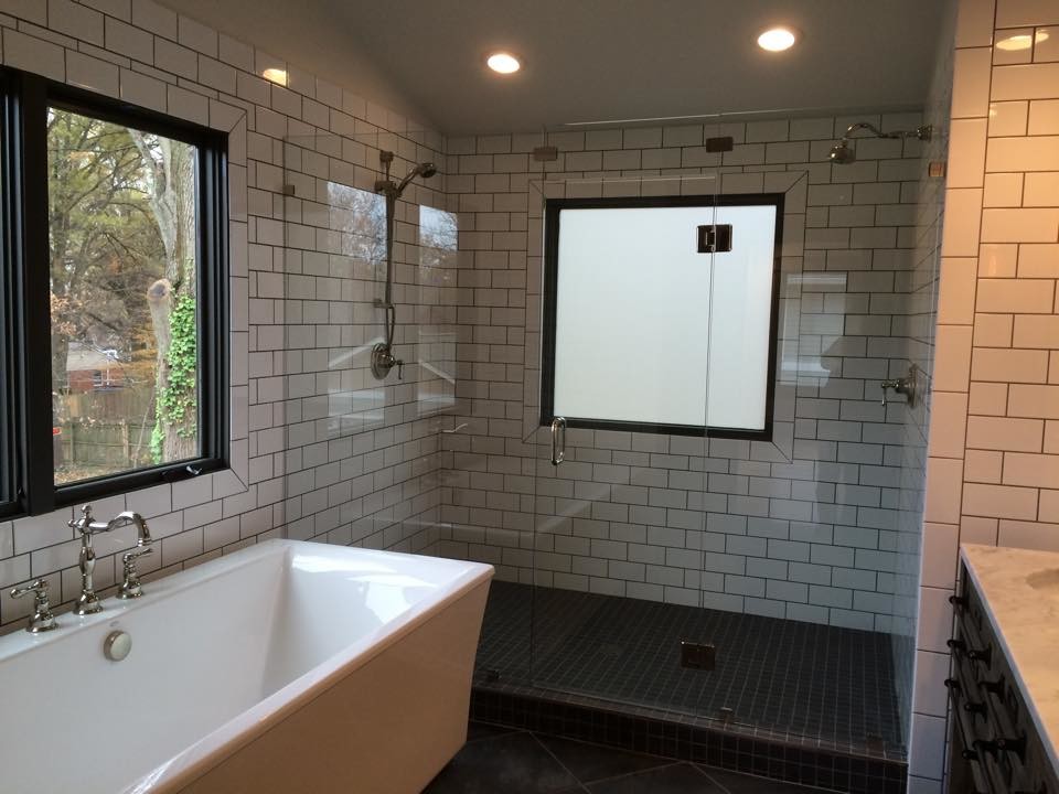 Design ideas for a mid-sized transitional master bathroom in Raleigh with recessed-panel cabinets, black cabinets, a freestanding tub, an alcove shower, white tile, subway tile, white walls, porcelain floors, an undermount sink, marble benchtops, grey floor and a hinged shower door.