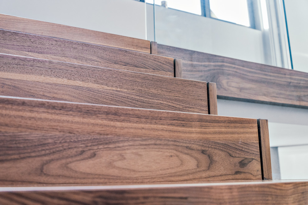 Photo of a large contemporary wood floating staircase in Cambridgeshire with wood risers and glass railing.