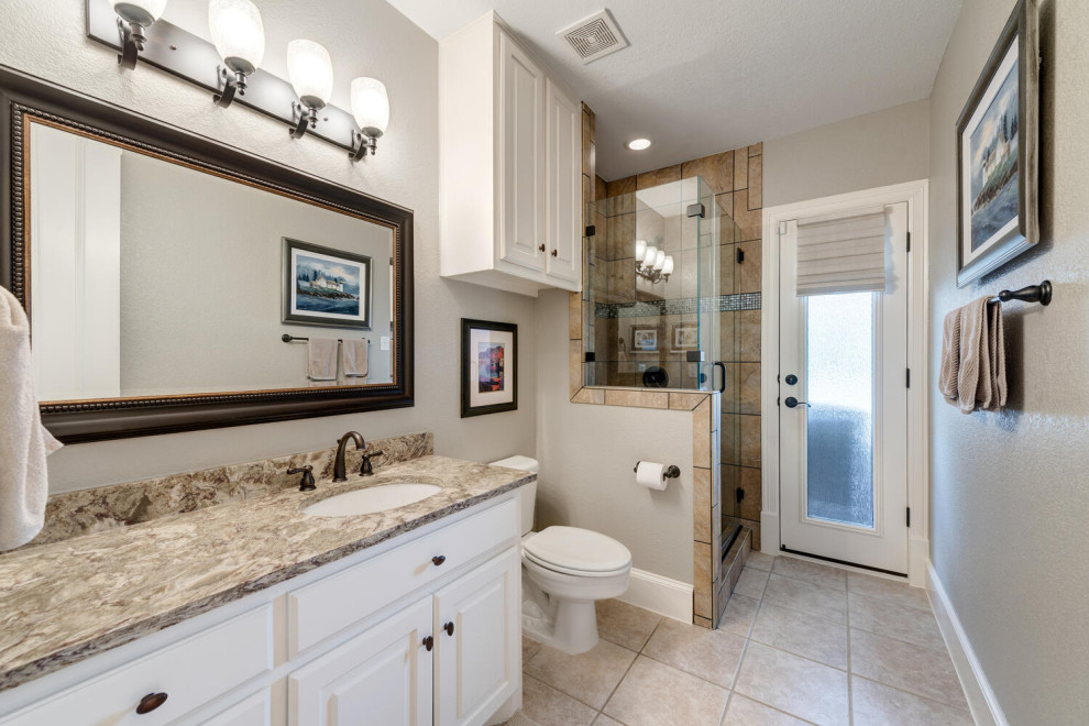 Design ideas for a large traditional 3/4 bathroom in Dallas with raised-panel cabinets, white cabinets, a corner shower, a one-piece toilet, gray tile, grey walls, porcelain floors, an undermount sink, granite benchtops, beige floor, a hinged shower door, beige benchtops, a single vanity and a built-in vanity.