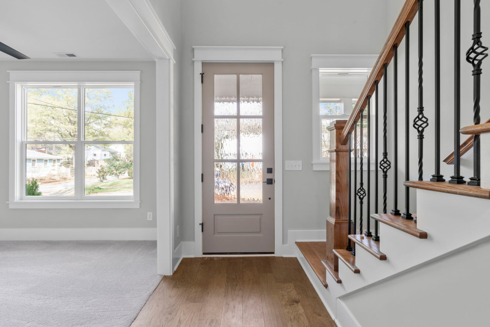 This is an example of a medium sized traditional front door in Raleigh with grey walls, a single front door, a grey front door, brown floors and light hardwood flooring.