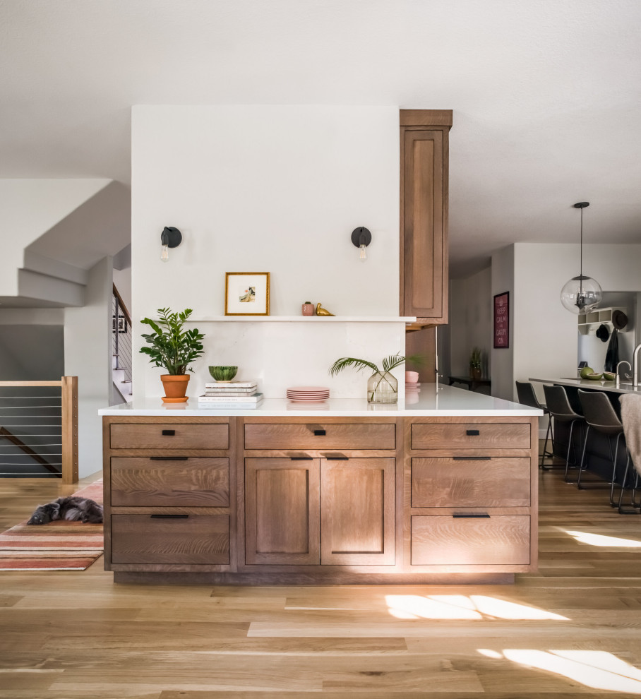 Design ideas for a mid-sized transitional galley open plan kitchen in Denver with with island, flat-panel cabinets, medium wood cabinets, stainless steel appliances, brown floor and white benchtop.
