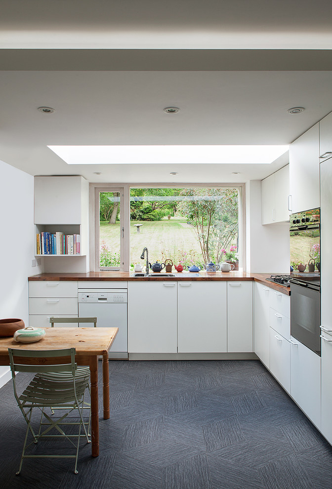 Design ideas for a mid-sized contemporary l-shaped eat-in kitchen in London with a double-bowl sink, flat-panel cabinets, white cabinets, wood benchtops, white splashback, stainless steel appliances, vinyl floors and grey floor.