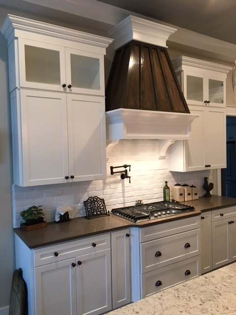 Large transitional l-shaped dark wood floor kitchen photo in Columbus with a farmhouse sink, shaker cabinets, white cabinets, quartzite countertops, white backsplash, brick backsplash, stainless steel appliances and an island