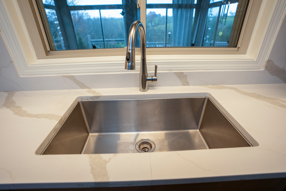 Inspiration for a large transitional l-shaped medium tone wood floor and brown floor eat-in kitchen remodel with a single-bowl sink, shaker cabinets, medium tone wood cabinets, quartz countertops, white backsplash, quartz backsplash, stainless steel appliances, an island and white countertops