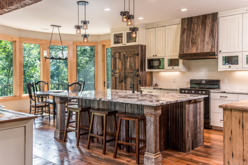 Enclosed kitchen - mid-sized rustic l-shaped medium tone wood floor and brown floor enclosed kitchen idea with a farmhouse sink, recessed-panel cabinets, white cabinets, granite countertops, white backsplash, subway tile backsplash, paneled appliances, an island and multicolored countertops